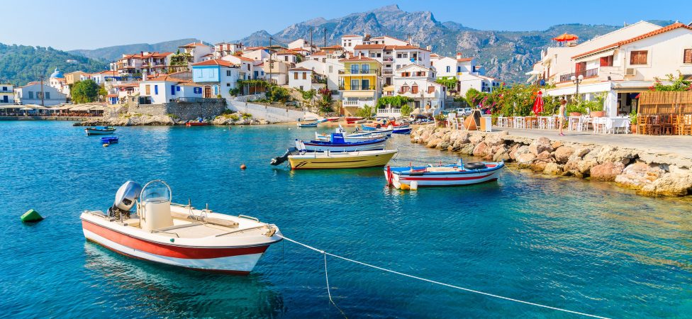 Fishing boats in Kokkari bay with colourful houses in background, Samos island, Greece